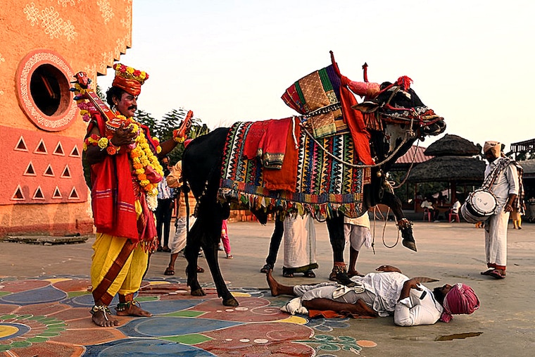 Performers, with a decorated bull, entertain visitors at the Shilparamam during the Sankranthi festival in Hyderabad on January 13, 2023.