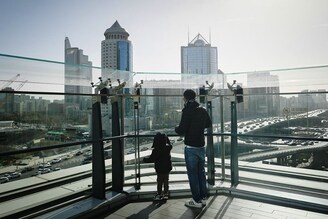 A Chinese citizen and his child look out at the Central Business District (CBD) in Beijing, China on January 17, 2023. China"s population has begun to shrink, a pivotal moment in the world’s most populous country, that experts say will be irreversible. It is the result of China"s one-child policy that it imposed between 1980 and 2015 as well as sky-high education costs that have put many off having more than one child.