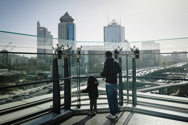 A Chinese citizen and his child look out at the Central Business District (CBD) in Beijing, China on January 17, 2023. China"s population has begun to shrink, a pivotal moment in the world’s most populous country, that experts say will be irreversible. It is the result of China"s one-child policy that it imposed between 1980 and 2015 as well as sky-high education costs that have put many off having more than one child.