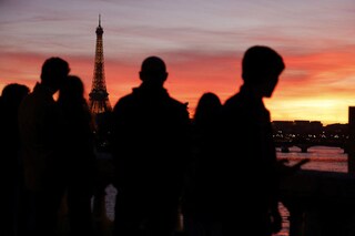 Tourists watch the Eiffel tower at sunset in Paris. Image Ludovic Marin/ AFP