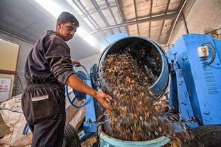 A worker dumps plastic waste out of a mixer before it is to be recycled into eco-friendly interlocking tiles used in outdoor walkways at a workshop of the startup company "TileGreen."
Image: Ahmed Hasan / AFP