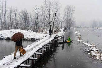 People walk on a snow-covered bridge as a boatman rows his boat under it during the snowfall in Srinagar. The Kashmir valley received a fresh snowfall that disrupted the normal lives of people. Flight operations, surface transport, and routine activities came to a grinding halt. Electricity was also affected in many areas of Kashmir. Jammu and Kashmir administration on Monday issued an alert of a high-danger level avalanche in several regions in the next 24 hours.