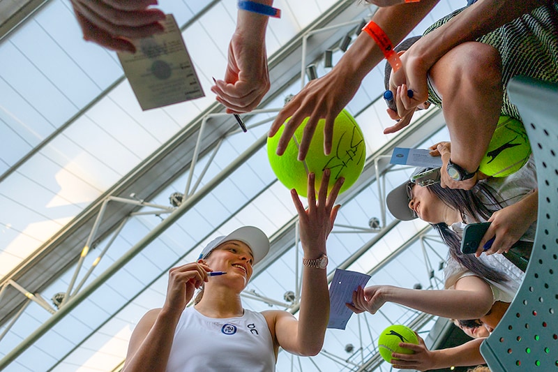 Iga Swiatek of Poland signs autographs for fans after her victory against Petra Martic of Croatia in the Ladies" Singles third-round match on Centre Court during the Wimbledon Lawn Tennis Championships at the All England Lawn Tennis and Croquet Club at Wimbledon on July 07, 2023, in London, England.