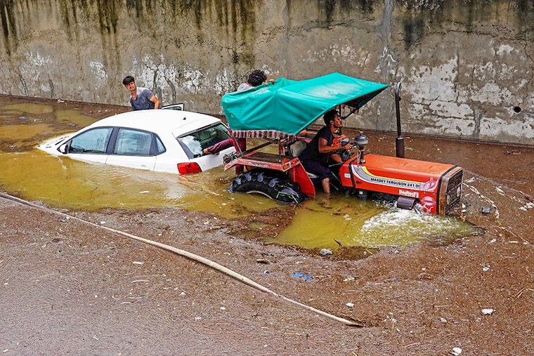A tractor tows a deluged car from a flooded street after heavy monsoon rains in Pushkar, Rajasthan, on July 10, 2023. The summer monsoon brings the South Asia region 70-80 percent of its annual rainfall, and economic loss, death, and destruction due to flooding and landslides.