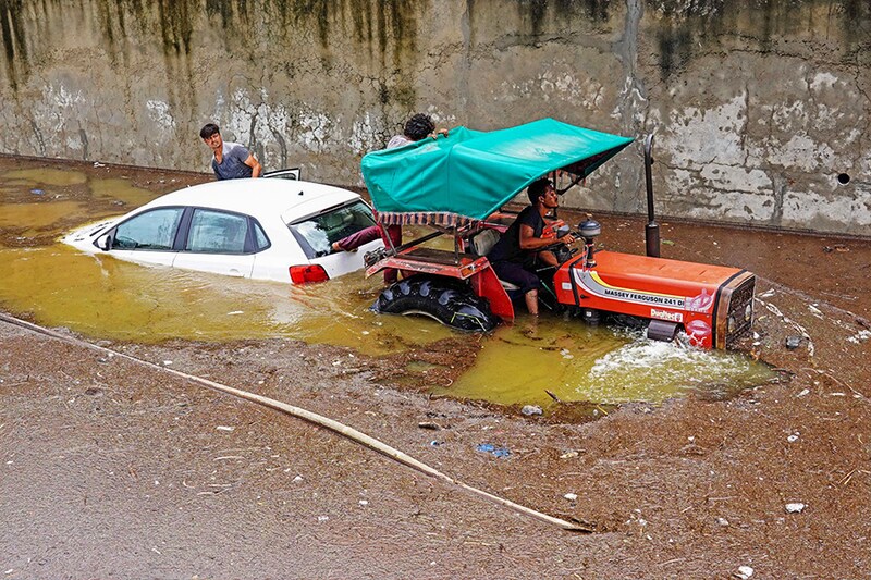 A tractor tows a deluged car from a flooded street after heavy monsoon rains in Pushkar, Rajasthan, on July 10, 2023. The summer monsoon brings the South Asia region 70-80 percent of its annual rainfall, and economic loss, death, and destruction due to flooding and landslides.