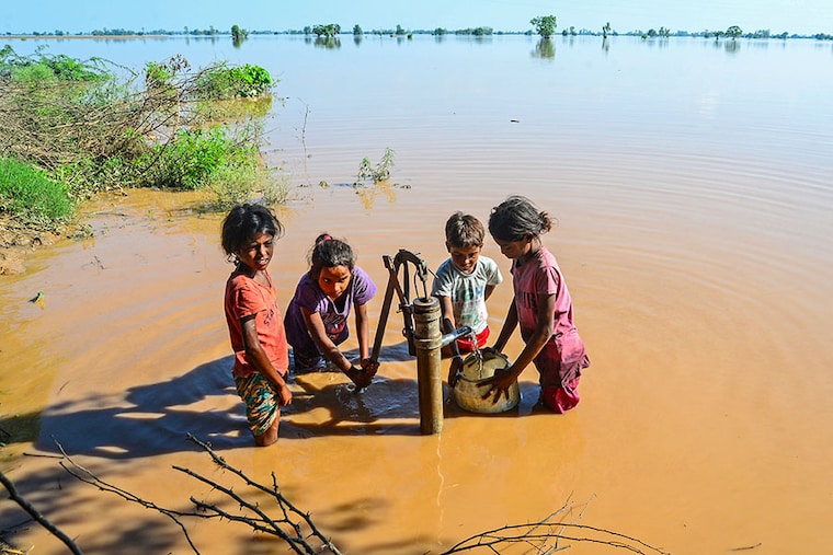 In this photograph taken on July 11, 2023, children fetch drinking water from a hand-pump in a flood-affected area after a breach in river Sutlej following heavy monsoon rains in Jalandhar district of India"s Punjab state. Days of intense monsoon rains across northern India have left at least 29 people dead, rendering many areas inaccessible with bridges smashed and roads blocked, officials said.