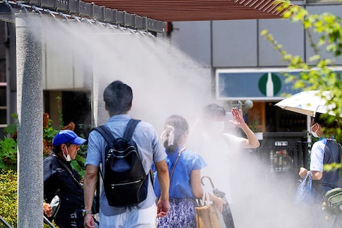 Pedestrians cool off in water mist during heatwave conditions in Tokyo on July 18, 2023.
Image: Kazuhiro Nogi / AFP Pedestrians cool off in water mist during heatwave conditions in Tokyo on July 18, 2023.
Image: Kazuhiro Nogi / AFP