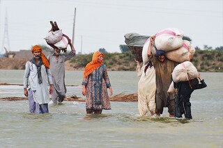 Villagers carrying animal feed wade through flood waters following monsoon rainfalls in Jaffarabad district in Balochistan province on August 24, 2022. - Record monsoon rains were causing a "catastrophe of epic scale", Pakistan"s Climate Change Minister said August 24, announcing an international appeal for help in dealing with floods that have killed more than 800 people since June. Image: Fida Hussain / AFP