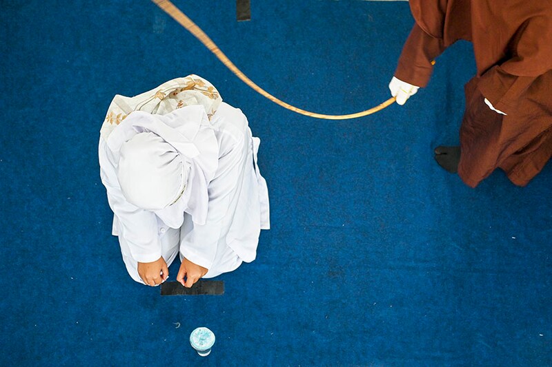 A woman is caned by a member of the Sharia police as punishment for being caught in close proximity with a man in Banda Aceh, Indonesia on June 7, 2023.