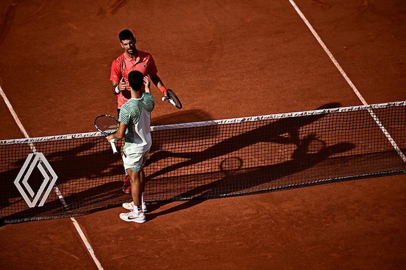 Serbia"s Novak Djokovic (back) shakes hands with Spain"s Carlos Alcaraz Garfia after his victory during their men"s singles semi-final match on day thirteen of the Roland-Garros Open tennis tournament at the Court Philippe-Chatrier in Paris on June 9, 2023.