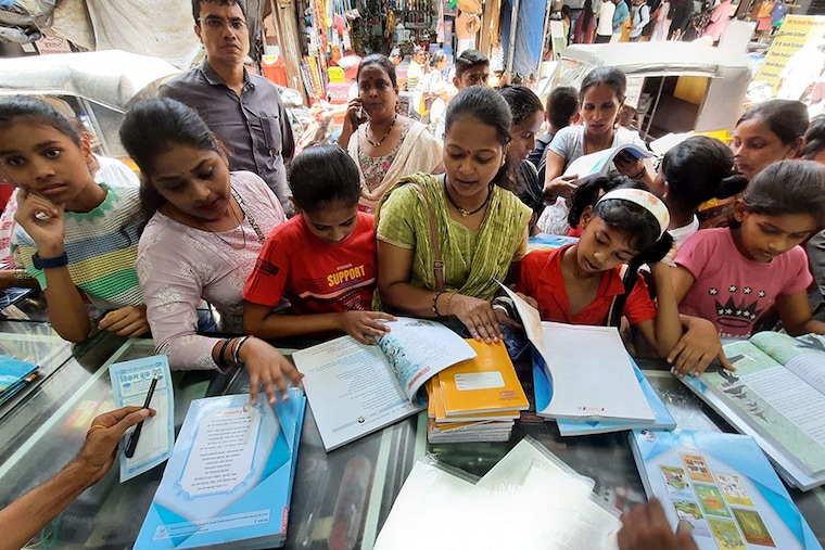 Parents help their children buy books and study materials at a stationery store before the reopening of schools on June 12, 2023, in Thane, India.