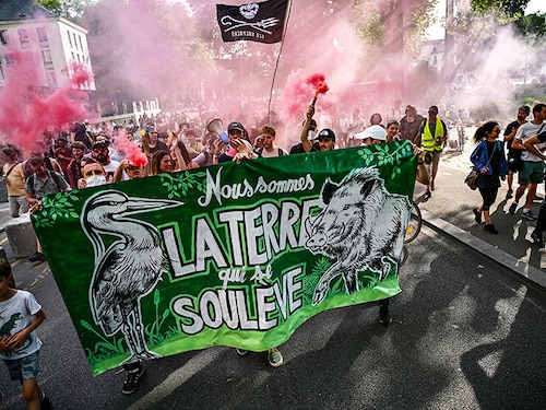 Protesters march behind a banner reading "We are the earth that rises up" during a rally to support the environmental movement "Les Soulevements de la Terre" (Uprisings of the Earth) in Nantes, western France on June 21, 2023, to protest against the decision by the government to dissolve the movement. Image: Loic Venance / AFP