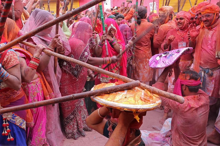 Women hit revellers with sticks, a traditional play during the spring festival celebration of Lathmar Holi, in Barsana village, Uttar Pradesh on February 28, 2023.