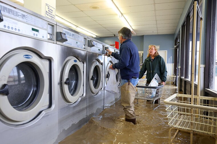 Patrick Cerruti and his wife Pamela take coins out of washing machines inside the flooded Pajaro Coin Laundry on March 14, 2023, in Pajaro, California. Northern California has been hit by another atmospheric river that has brought heavy rains and flooding throughout the region. The town has been inundated with floodwaters since Saturday after a levee was breached along the Pajaro River.