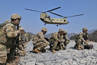 US soldiers take a position as a Chinook helicopter prepares to land during a field artillery battalion gun raid drill at a military training field in Pocheon, South Korea on March 19, 2023. South Korea and the United States kicked off the Freedom Shield joint military exercise, their largest drills in five years as part of the allies" drive to counter North Korea"s growing threats.