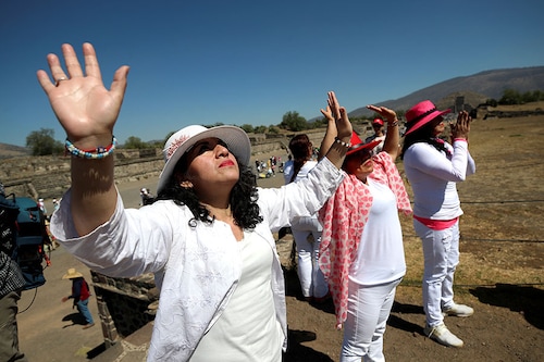 People raise their hands to "charge themselves with energy" in front of the Pyramid of the Sun, a 1800-year old towering monument, on the day of the spring equinox in the ancient city of Teotihuacan, on the outskirts of Mexico City, Mexico, March 20, 2023.
