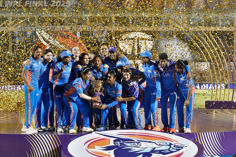 The Mumbai Indians team poses with the series trophy after winning the Women"s Premier League against Delhi Capitals at Brabourne Stadium on March 26, 2023, in Mumbai, India.