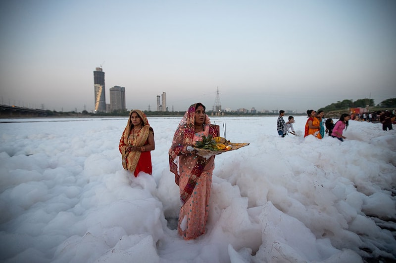 Devotees perform rituals to the sun god in the Yamuna river sheathed by a layer of toxic foam caused by industrial effluents, on the occasion of Chaiti Chhath Puja festival in New Delhi, India, on March 27, 2023.