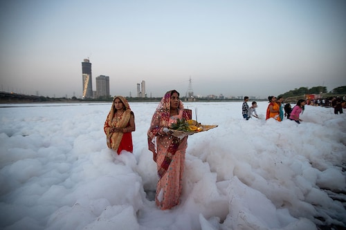 Devotees perform rituals to the sun god in the Yamuna river sheathed by a layer of toxic foam caused by industrial effluents, on the occasion of Chaiti Chhath Puja festival in New Delhi, India, on March 27, 2023.