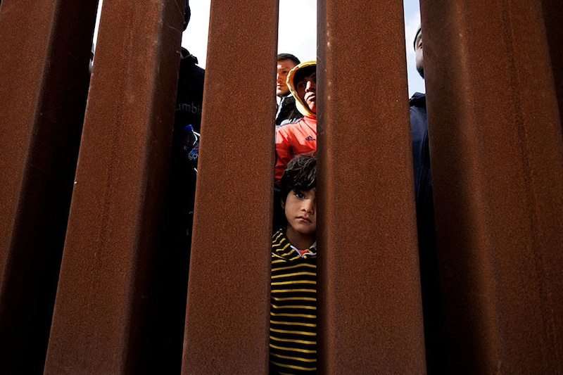 A young migrant peers through the border fence in San Diego as the United States prepares to lift Covid-19-era restrictions known as Title 42. The policy blocked migrants at the US-Mexico border from seeking asylum since 2020.