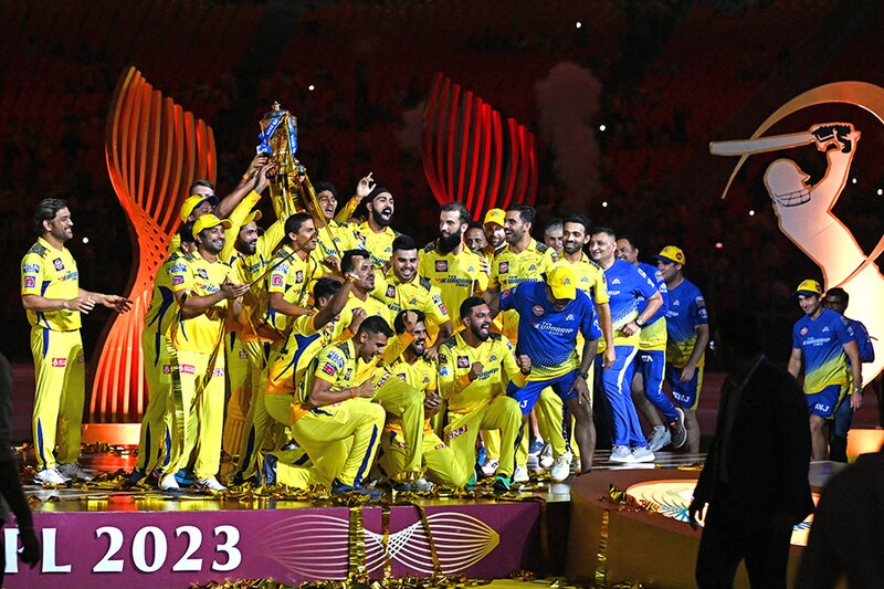 Chennai Super Kings" captain MS Dhoni (extreme left) looks at his winning team as they lift the IPL trophy in celebration after the IPL T20 final cricket match at the Narendra Modi Stadium in Ahmedabad on May 30, 2023. CSK beat Gujarat Titans in a last ball thriller amidst a record crowd of over a lakh who patiently endured a long rain delay.