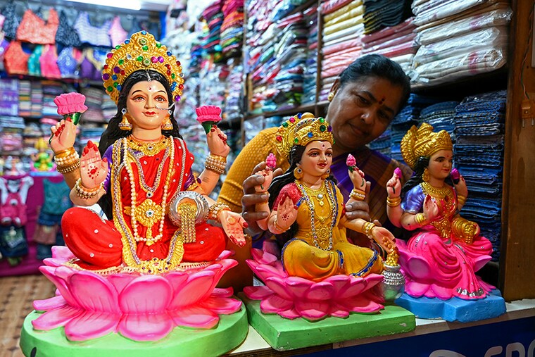A seller adjusts miniature "Laxmi" deities at a shop in Hyderabad on November 10, 2023, ahead of Diwali, the festival of lights