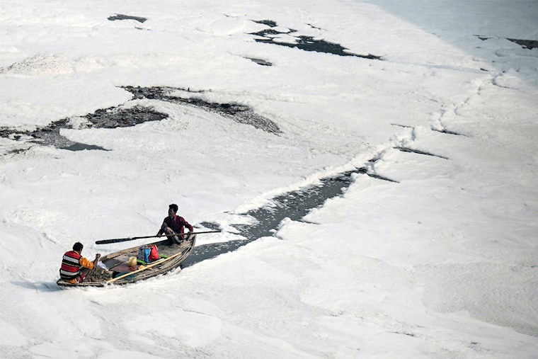 A boatman steers a boat in the polluted waters of the Yamuna River in New Delhi on November 23, 2023. Image: Money Sharma / AFP