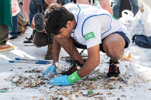 A member of India sorts through rubbish at the end of the first round of the "SpoGOMI World Cup 2023" final.
Image: Richard A. Brooks / AFP