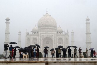 Tourists use umbrellas to shelter from the rain while visiting the Taj Mahal in Agra on November 30, 2023. Image: Pawan Sharma / AFP