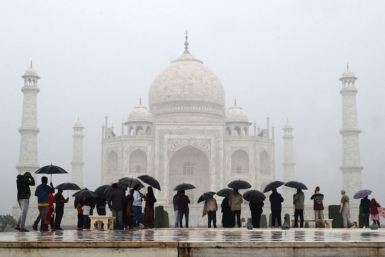 Tourists use umbrellas to shelter from the rain while visiting the Taj Mahal in Agra on November 30, 2023. Image: Pawan Sharma / AFP
