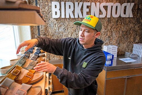 Employee Mo Soto arranges a shelf at a Birkenstock store on October 10, 2023 in Venice, California. German footwear company Birkenstock is reportedly planning to offer 32.3 million shares priced at $44 to $49, and is expected to attain a valuation of $9.2 billion.  Image: Ethan Swope/Getty Images/AFP