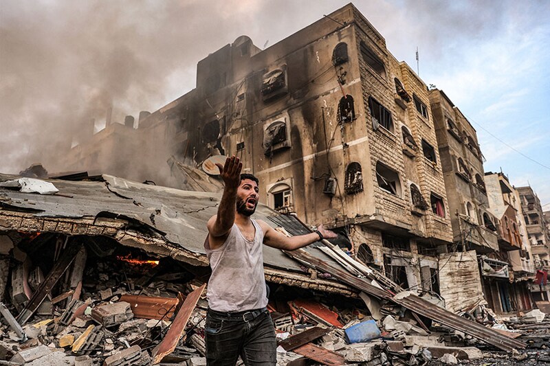 A man reacts outside a burning collapsed building following Israeli bombardment in Gaza City. Death toll in the latest strikes between Hamas and Israel has crossed over 1,400 in the Gaza Strip. The Israeli military confirmed it had hit several Hamas targets during the night in the Palestinian enclave on October 12.