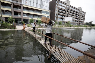 People walk on a makeshift bridge above a waterlogged street in Ahmedabad Image: Amit Dave/ Reuters