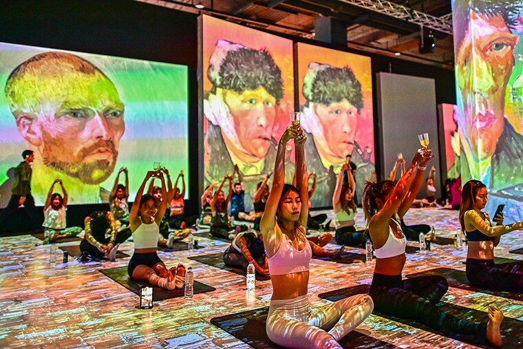 Yoga enthusiasts hold wine glasses during a Brew-Yoga event as part of an immersive art exhibition of renowned Dutch artist, Vincent Van Gogh, titled "Van Gogh Alive" in Bangkok, on September 2, 2023. Image: Manan Vatsyayana/AFP