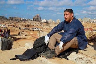 A volunteer sits on the rubble of a building in a flash flood-damaged area in Derna on September 14, 2023. A global aid effort for Libya gathered pace on September 14 after a tsunami-sized flash flood killed at least 4,000 people, with thousands more missing, a death toll the UN blamed in part on the legacy of years of war and chaos.