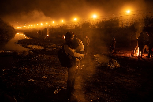 Stephani, a 28-year-old migrant from Venezuela, holds her four-year-old son Estefan near a smouldering fire along a dry stretch of the Rio Grande River after arriving at an encampment of migrants searching for an entry point into the United States from the international boundary between Ciudad Juarez, Mexico and El Paso, Texas, US, April 3, 2024.