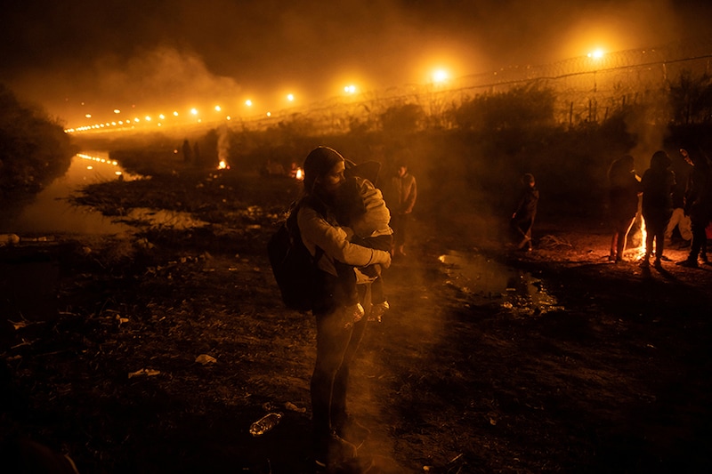 Stephani, a 28-year-old migrant from Venezuela, holds her four-year-old son Estefan near a smouldering fire along a dry stretch of the Rio Grande River after arriving at an encampment of migrants searching for an entry point into the United States from the international boundary between Ciudad Juarez, Mexico and El Paso, Texas, US, April 3, 2024.