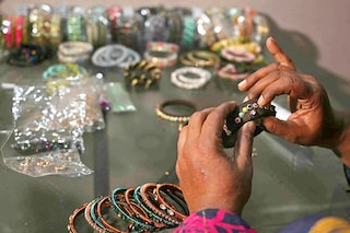 Talat Zahid adds decorative elements to bangles at a home workshop in Hyderabad. <br>Image: Asif Hassan / AFP©