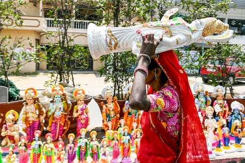A vendor carries an idol of Lord Ram to arrange it along with other Hindu deities by the roadside in Hyderabad on April 16, 2024, on the eve of Ram Navami festival.