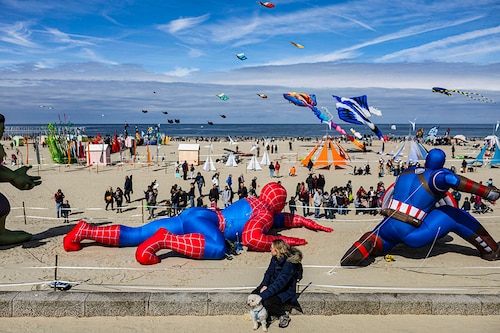 A woman watches people flying kites during the 37th International Kite Festival (RICV) at the beach of Berck-sur-Mer, northern France, on April 23, 2024.