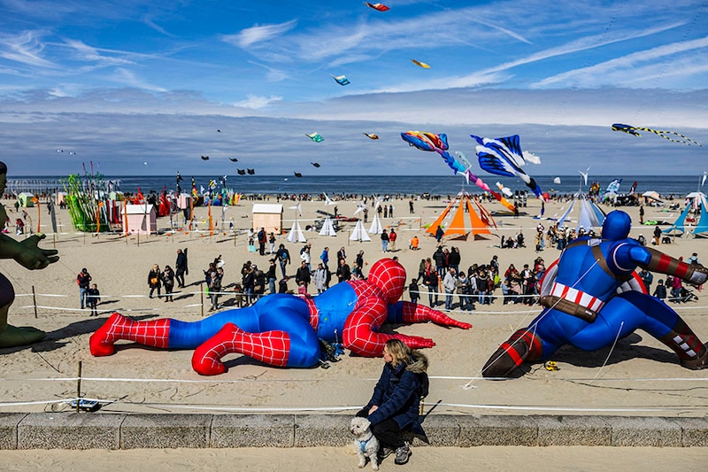 A woman watches people flying kites during the 37th International Kite Festival (RICV) at the beach of Berck-sur-Mer, northern France, on April 23, 2024.