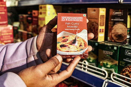 A shopkeeper is holding packets of Everest"s Fish Curry Masala at a department store in Baramulla, Jammu and Kashmir, India, on April 23, 2024. The said masala has been put under the scanner in Singapore for containing cancer causing chemicals. Image: Getty Images