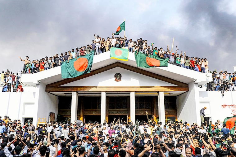 Anti-government protestors display Bangladesh"s national flag as they storm Prime Minister Sheikh Hasina"s palace in Dhaka on August 5, 2024. Bangladesh army chief Waker-Uz-Zaman spent nearly four decades rising to the top of the military and said on August 5 that he was "taking full responsibility" after Prime Minister Sheikh Hasina was ousted and fled.
