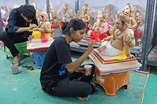 A young woman paints an idol of the elephant-headed god Ganesh at a workshop in Mumbai on August 12, 2024, ahead of the Ganpati festival.