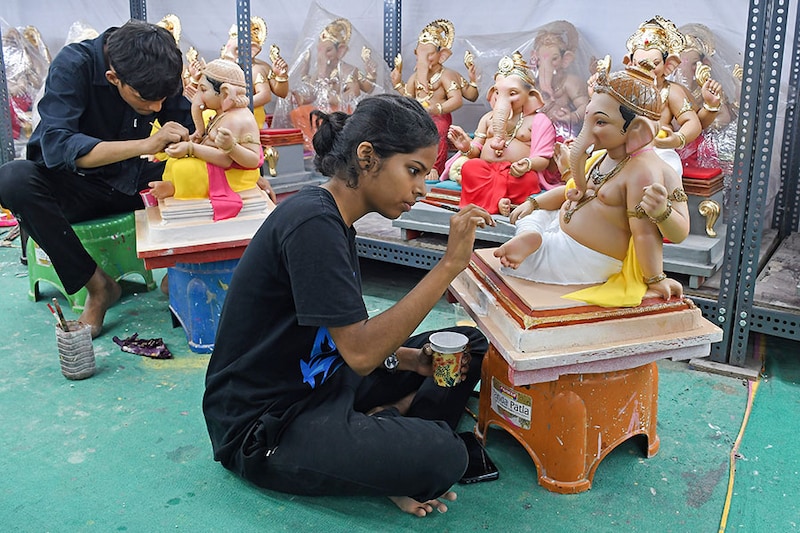 A young woman paints an idol of the elephant-headed god Ganesh at a workshop in Mumbai on August 12, 2024, ahead of the Ganpati festival.
