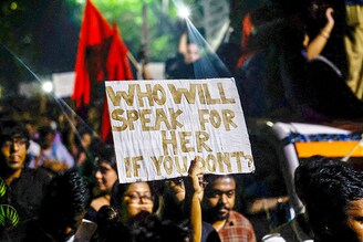 Woman holds a placard as she attends a candlelight vigil held outside Jadavpur University campus on August 15, 2024, condemning the rape and murder of a trainee doctor at a government-run hospital, RG Kar, in Kolkata, India.