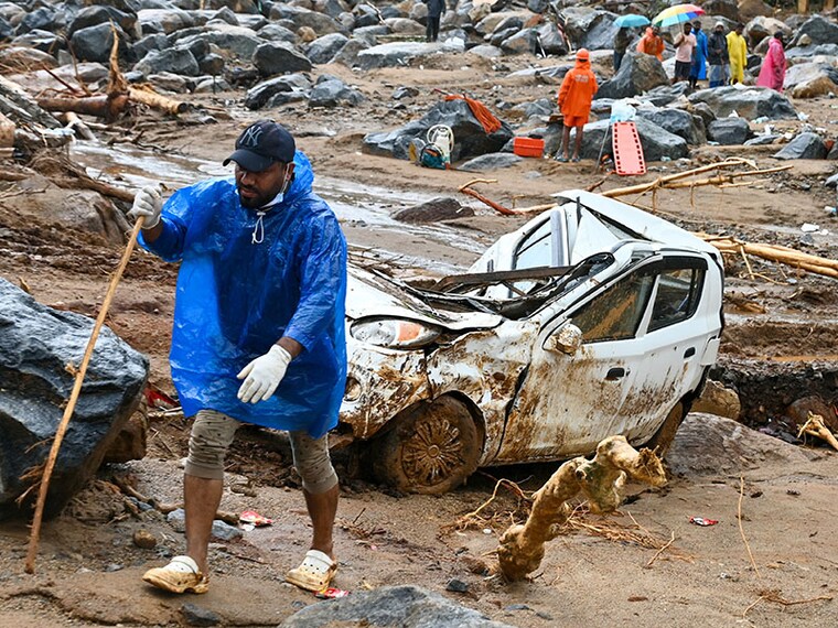A man walks past a damaged vehicle after the landslides in Wayanad on August 1, 2024. - Indian rescue crews scoured mud-caked tea plantations and villages on August 1 with little hope of finding more survivors from landslides that killed around 200 people.Â <br> Image: Idrees Mohammed / AFP