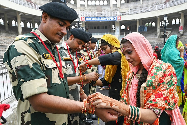 Young women tie rakhi, a sacred thread, onto the wrists of Border Security Force (BSF) personnel on the occasion of Raksha Bandhan festival at the India-Pakistan Wagah border post, about 35kms from Amritsar on August 19, 2024.