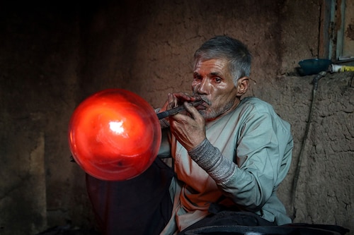 Ghulam Sakhi Saifi, an Afghan glassblower, crafts a glassware at his traditional workshop in Afghanistan"s western city of Herat. 
Image: Mohsen Karimi / AFPÂ©