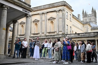 Visitors listen to tour guide Ruby Maidment during a visit to discover the sets of the Netflix series "Bridgerton", in Bath, western England, on July 16, 2024. Image credit: Photography Justin TALLIS / AFP